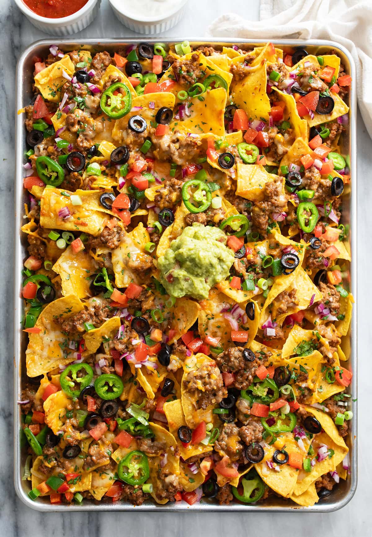 A tray of Loaded Nachos with beef, refried beans, cheese, olives, jalapenos, and more.