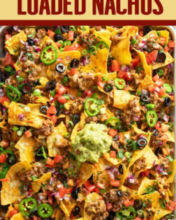 A labeled image of Loaded Nachos on a sheet pan with a scoop of guacamole on top.