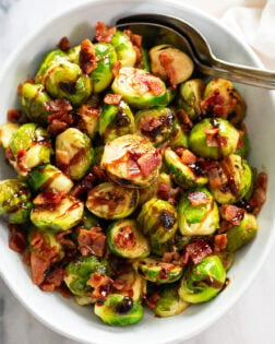 Overhead view of Bacon Brussels Sprouts in a white bowl with balsamic glaze on top.