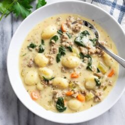 Sausage Gnocchi Soup in a white bowl with spinach, sausage, carrots, and gnocchi.