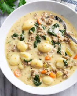 Sausage Gnocchi Soup in a white bowl with spinach, sausage, carrots, and gnocchi.