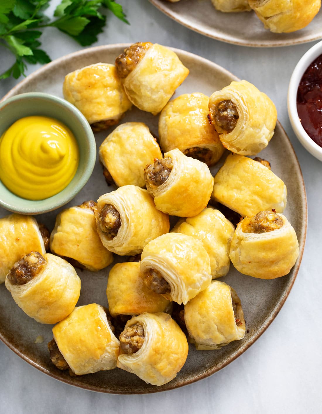 Overhead view of Sausage Rolls on a plate with a ramekin of mustard on the side.