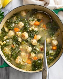 Chicken Meatball Soup in a pot with a ladle on the side.