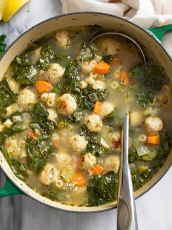 Chicken Meatball Soup in a pot with a ladle on the side.