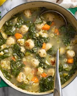 Chicken Meatball Soup with spinach, chicken meatballs, and pasta with a ladle on the side.