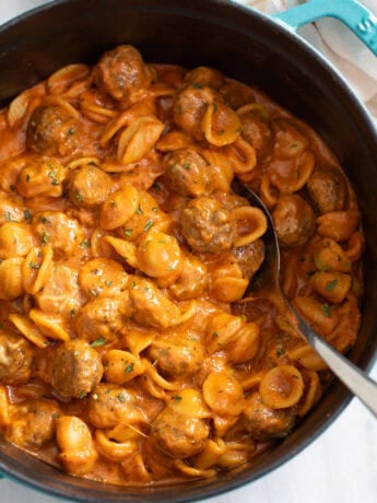 Meatball Pasta in a Dutch Oven with a spoon on the side.