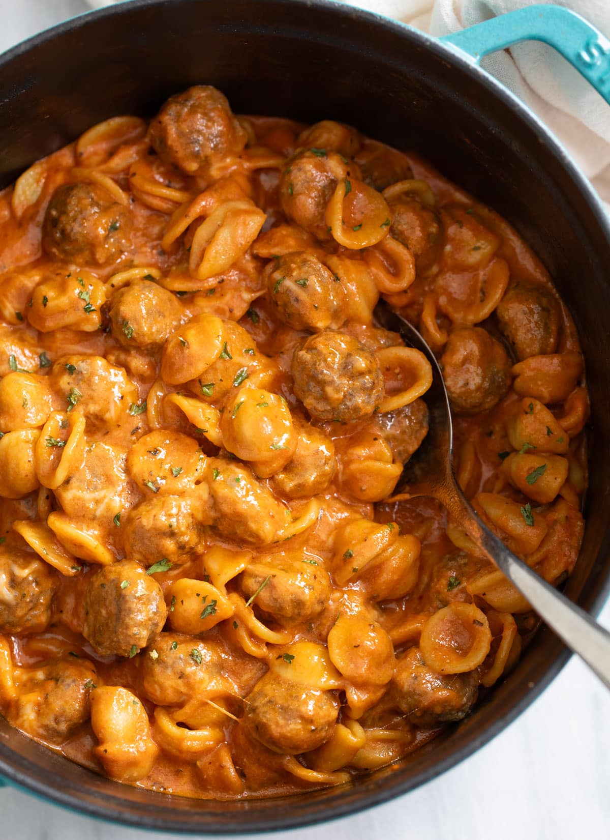 Meatball Pasta in a Dutch Oven with a spoon on the side.