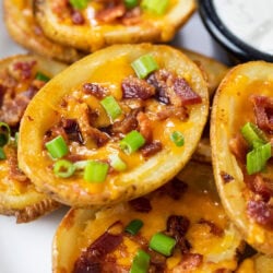 Potato Skins stacked up on a plate with sour cream.