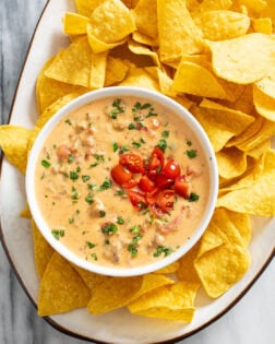 Rotel Dip in a white bowl on a serving platter with tortilla chips.