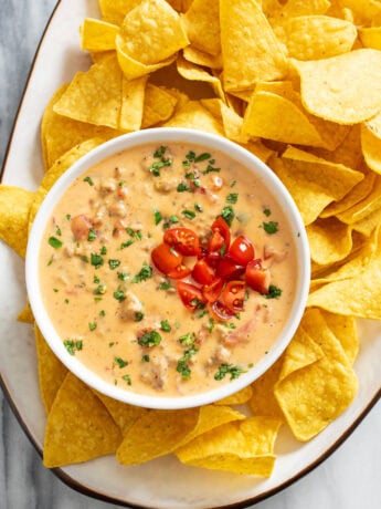 Rotel Dip in a white bowl on a serving platter with tortilla chips.