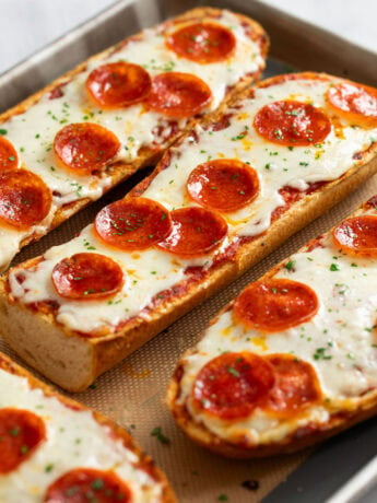 French Bread Pizza on a baking sheet topped with melted mozzarella and pepperoni.