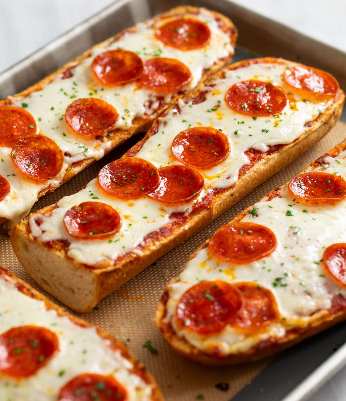 French Bread Pizza on a baking sheet topped with melted mozzarella and pepperoni.