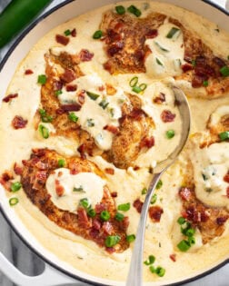 A skillet filled with Jalapeno Popper Chicken in a cream sauce with bacon and green onions.