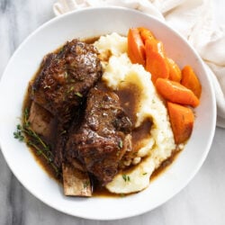 Slow Cooker Short Ribs on a white plate with mashed potatoes and carrots.