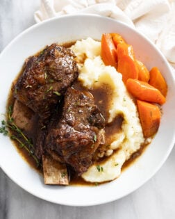 Slow Cooker Short Ribs on a white plate with mashed potatoes and carrots.