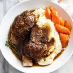 Slow Cooker Short Ribs on top of mashed potatoes with Au Jus and carrots.