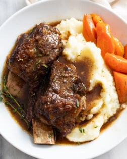 Slow Cooker Short Ribs on top of mashed potatoes with Au Jus and carrots.