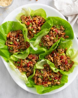 Chicken Lettuce Wraps with chicken, carrots, bell peppers, and toppings on a white platter.