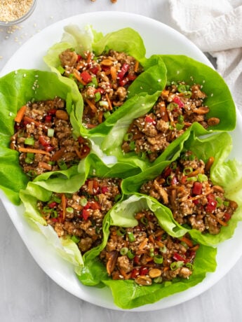Chicken Lettuce Wraps with chicken, carrots, bell peppers, and toppings on a white platter.