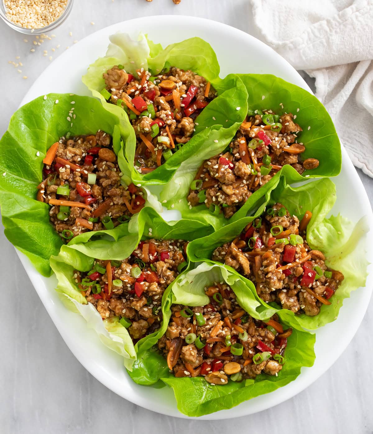 Chicken Lettuce Wraps with chicken, carrots, bell peppers, and toppings on a white platter.
