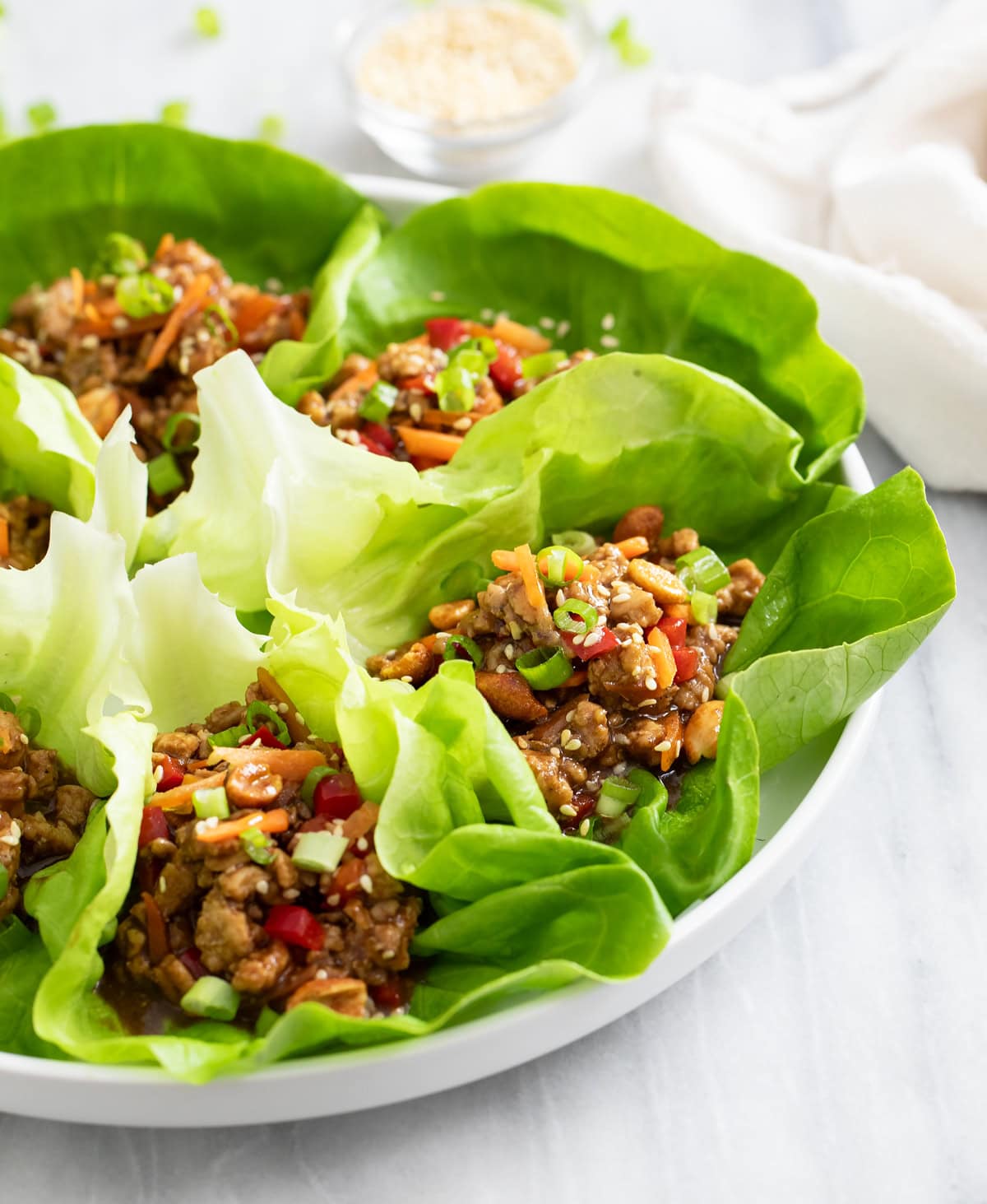 A side view of Chicken Lettuce Wraps on a white plate.