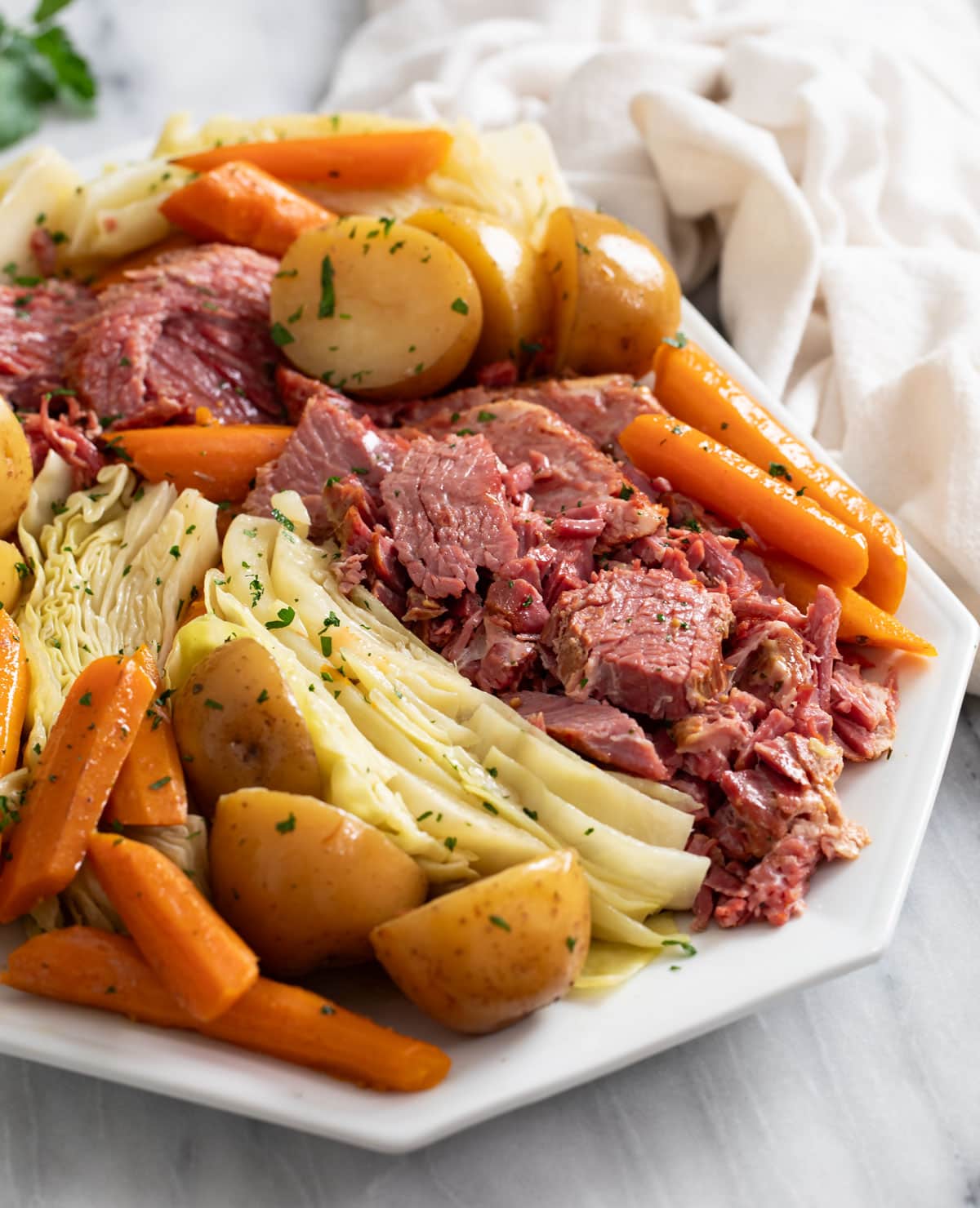 Corned Beef and Cabbage on a white platter with carrots and potatoes.