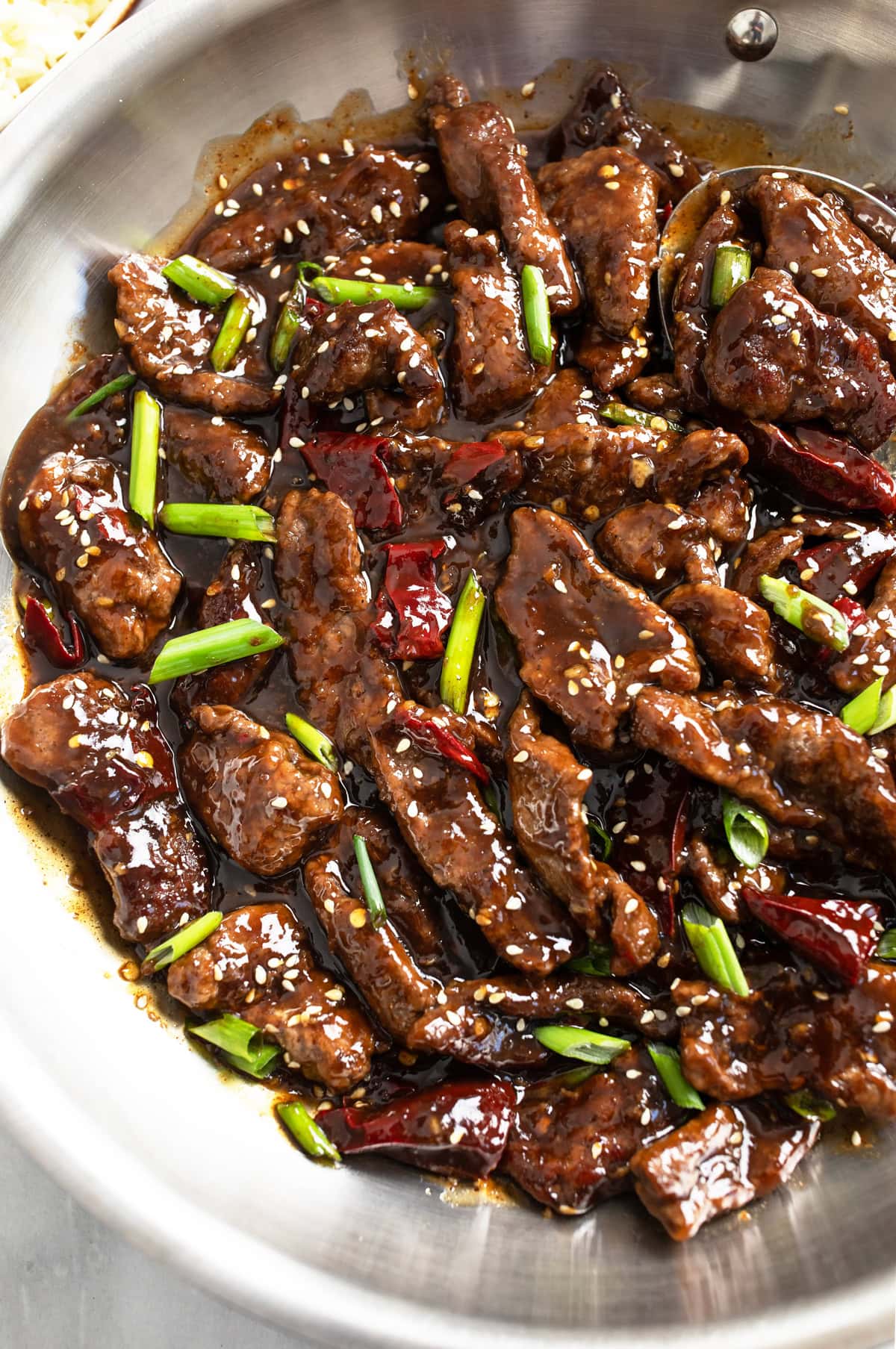 Mongolian Beef in a skillet with green onions and dried red chilies.