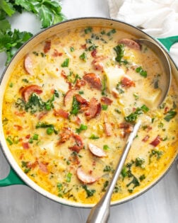 Kielbasa Potato Soup in a green soup pot with a ladle on the side.