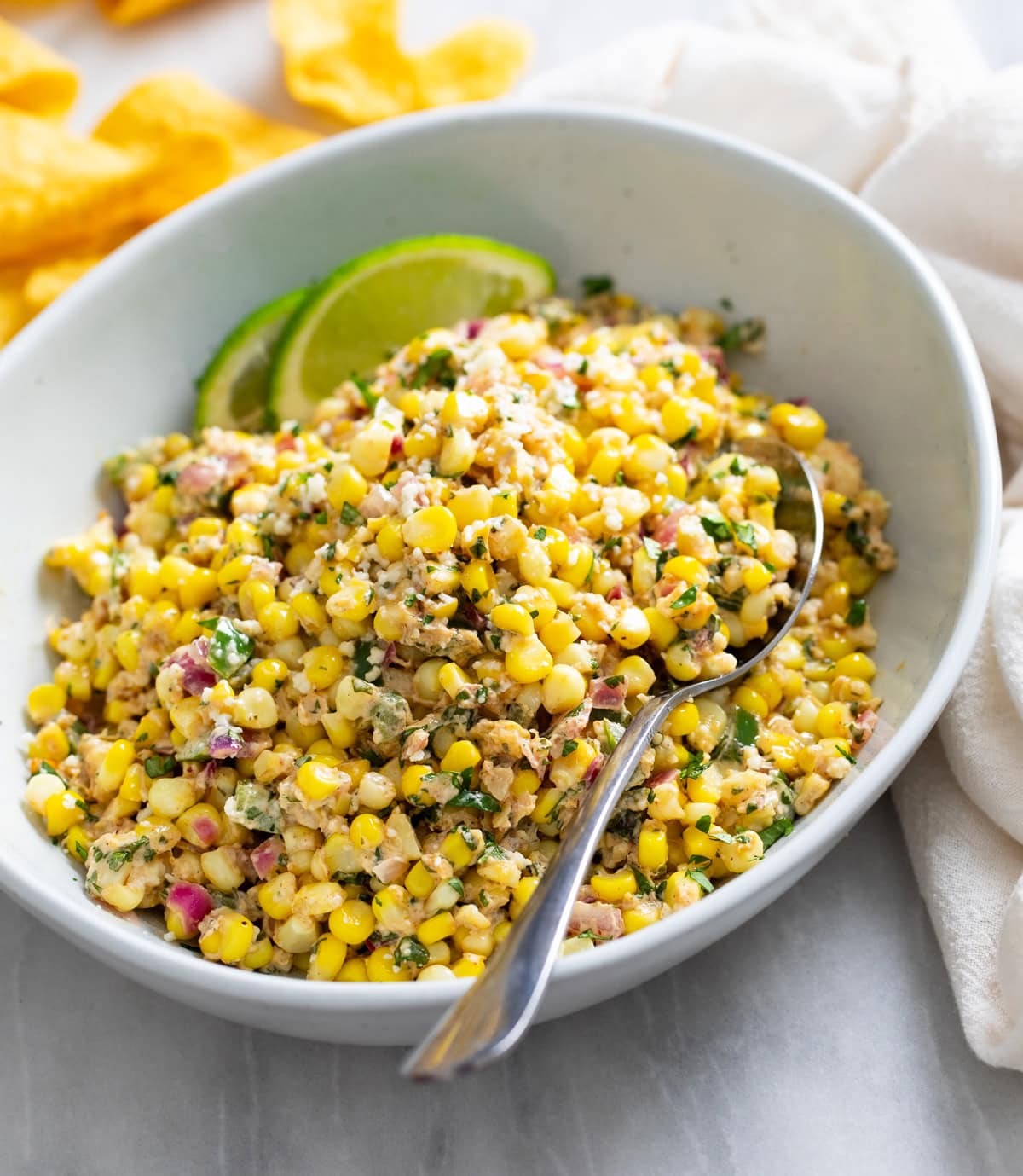 Side view of a bowl of Mexican Street Corn Salad with a spoon on the side.