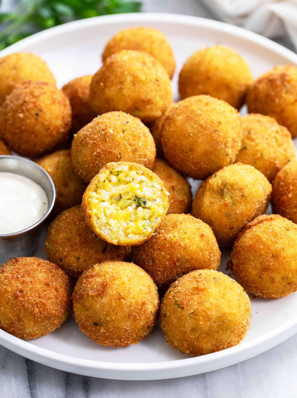 Fried Rice Balls on a white plate with a cheesy broccoli rice filling inside.