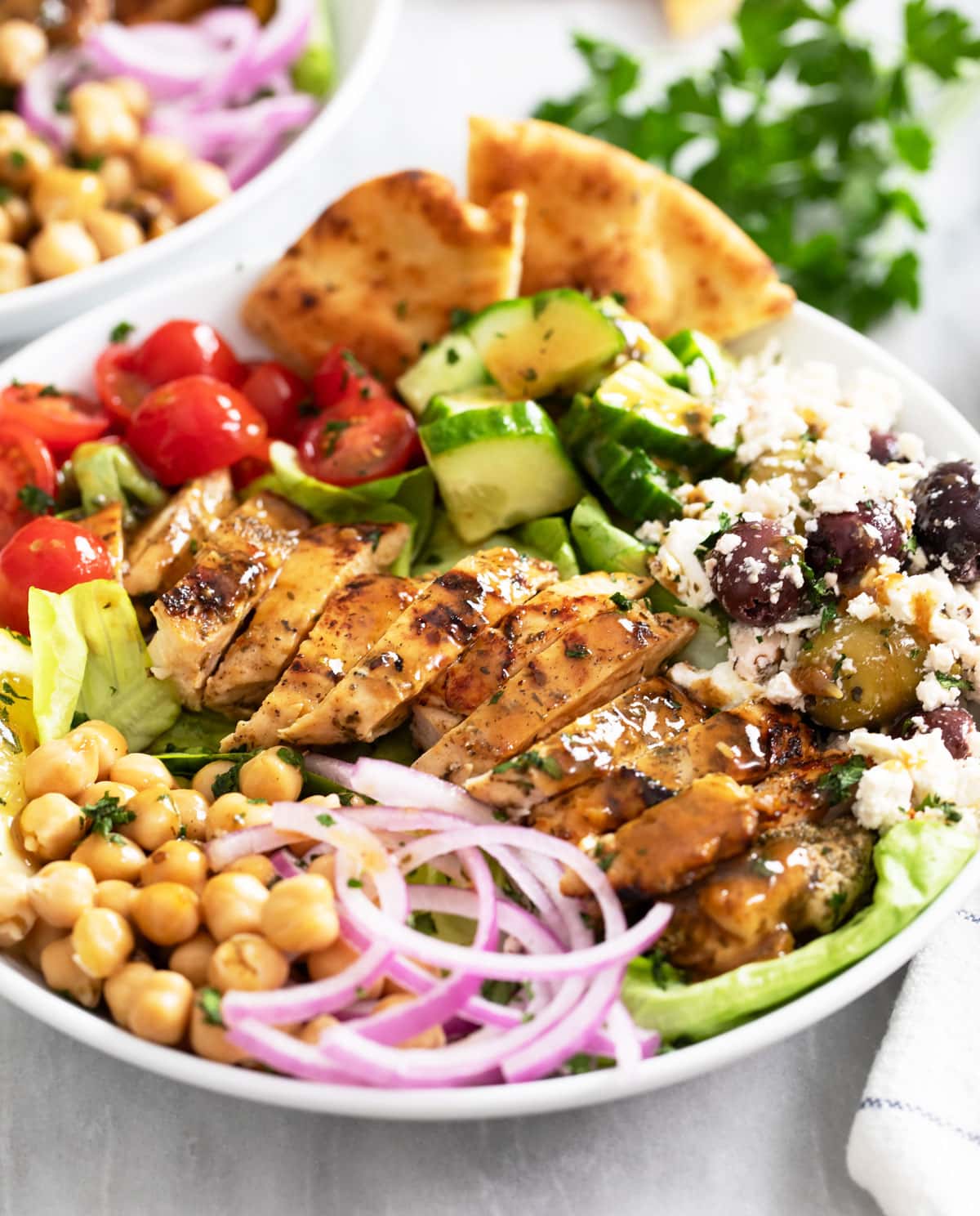 Greek Chicken Bowls with chicken, chickpeas, onions, cucumbers, tomatoes, feta, olives, and more.
