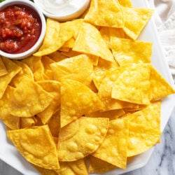 Homemade Tortilla Chips on a white plate with salsa and sour cream.