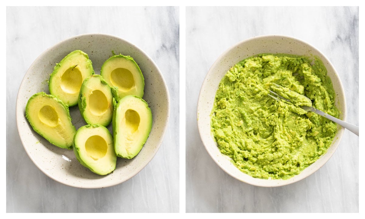 A bowl of halved and pitted avocados next to a bowl of mashed avocado with a fork on the side.