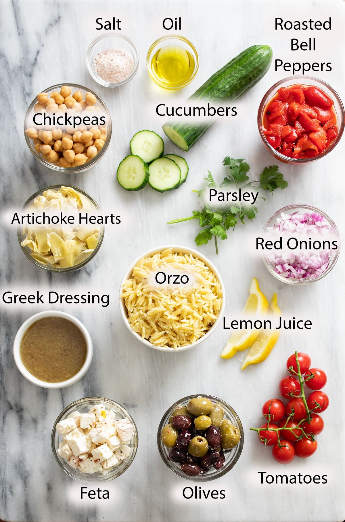 Labeled ingredients for making Orzo Salad on a white surface.