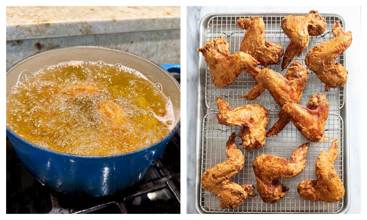 A pot with chicken wings frying next to cooling racks with fried chicken wings on top.
