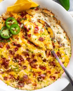 A spoon scooping up Jalapeno Popper Dip from a baking dish.