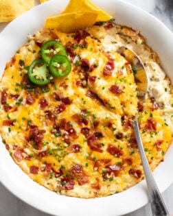 Jalapeno Popper Dip in a white baking dish with sliced jalapenos on top.