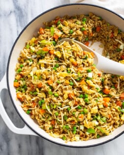 A white skillet with Vegetable Fried Rice and a white spoon on the side.