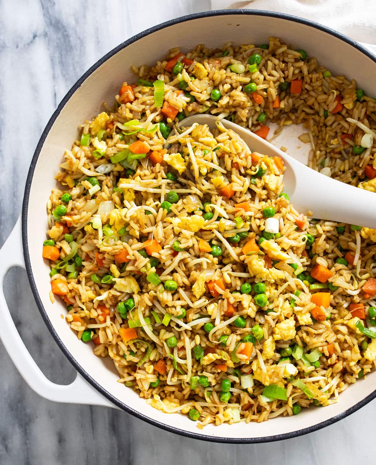 A white skillet with Vegetable Fried Rice and a white spoon on the side.