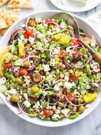 Overhead view of classic Greek Salad with vegetables, feta, chickpeas, and homemade dressing.