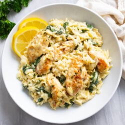 Lemon Chicken Orzo in a white bowl with lemon slices on the side.