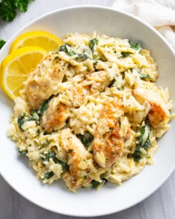 Lemon Chicken Orzo in a white bowl with lemon slices on the side.