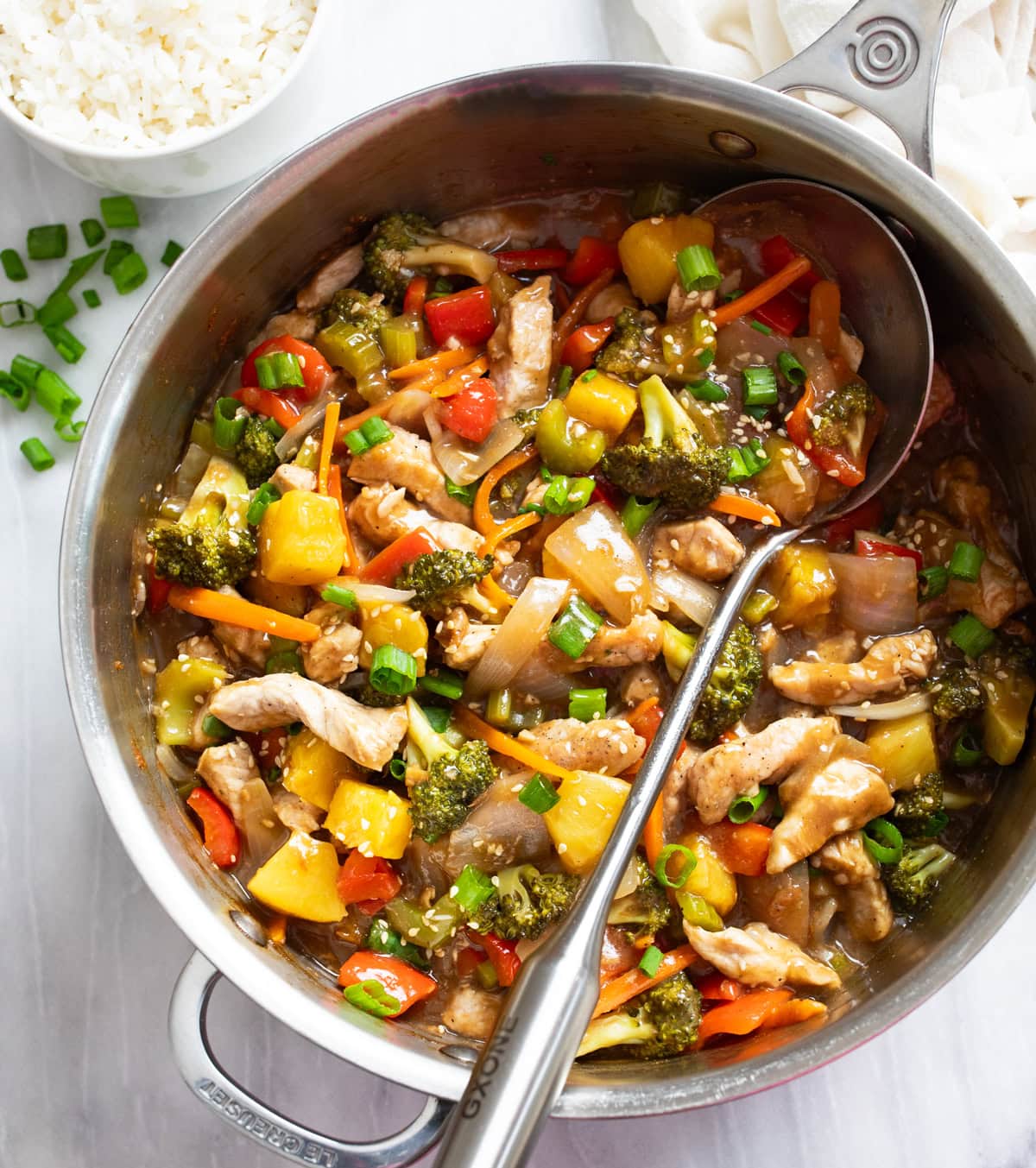 Pork Stir Fry in a skillet with sauce and vegetables with a spoon on the side.