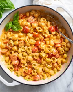 Cherry Tomato Pasta in a white skillet with a tomato cream sauce, herbs, and a spoon on the side.