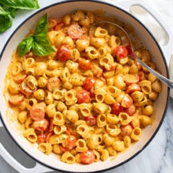 A white skillet filled with Cherry Tomato Pasta in a tomato cream sauce with herbs.