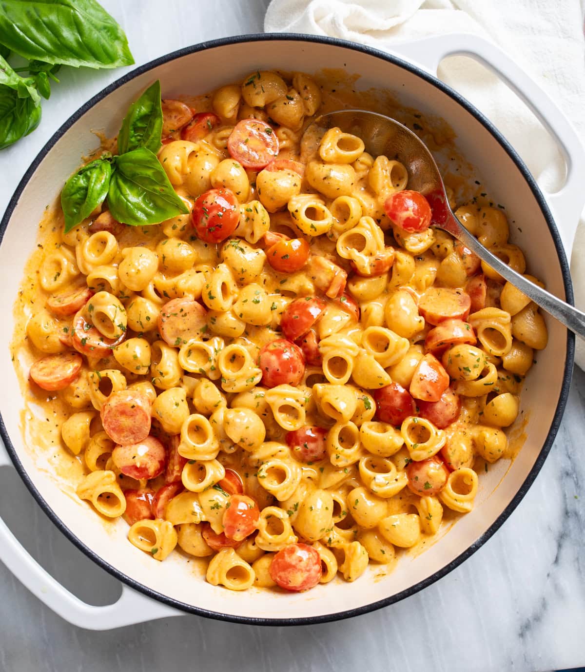 Cherry Tomato Pasta in a white skillet with a tomato cream sauce, herbs, and a spoon on the side.