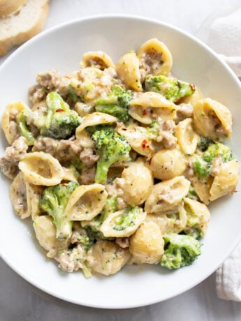 A white bowl with Sausage and Broccoli Pasta in a creamy sauce.