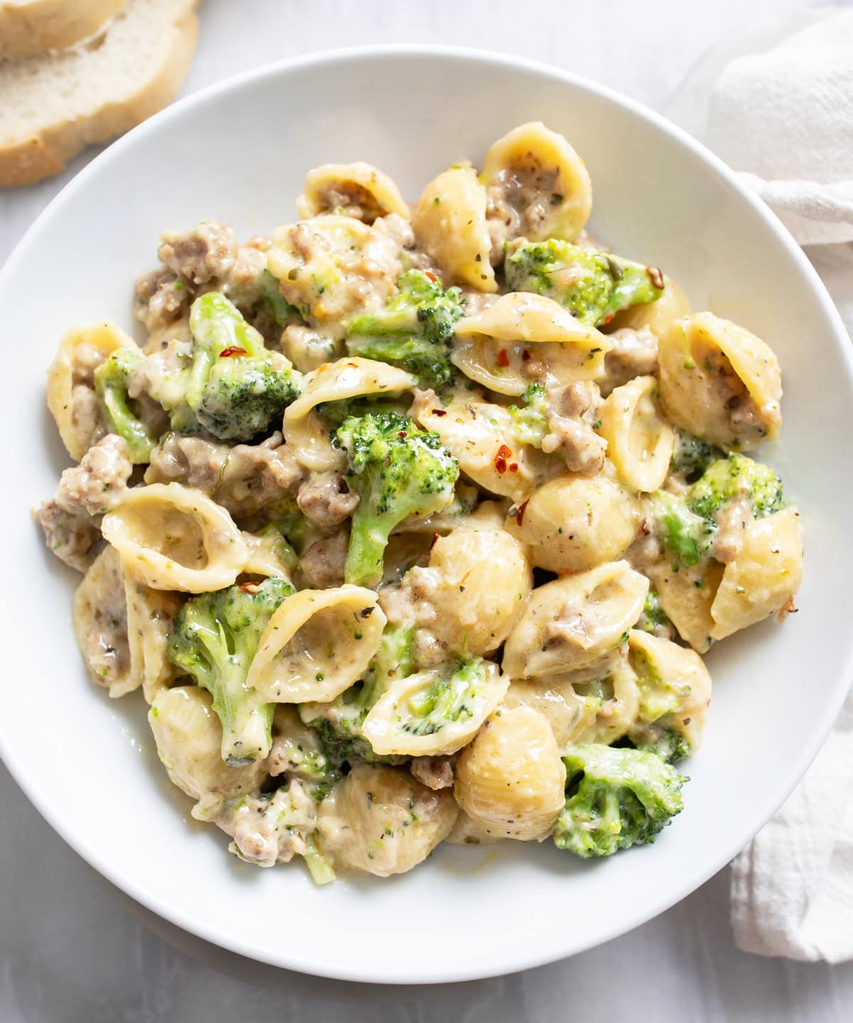 A white bowl with Sausage and Broccoli Pasta in a creamy sauce.