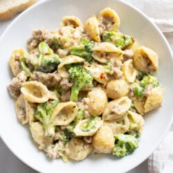 Creamy Sausage and Broccoli Pasta in a white bowl with red pepper flakes on top.