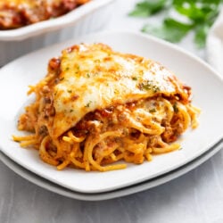 A slice of Spaghetti Pie on a stack of white plates.